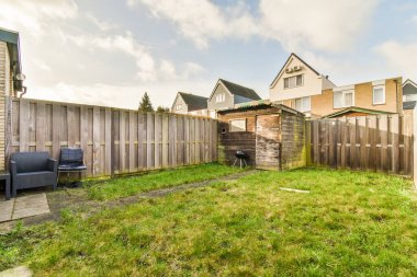 Oturma alanı ve ahşap çitlerin yanındaki küçük bahçesi olan düzgün asfaltlı bir avlu.