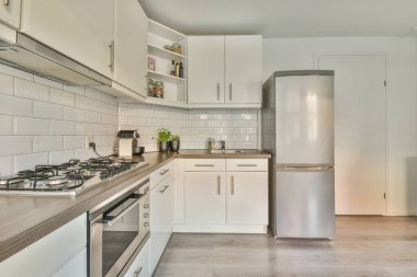 Beyaz duvarlı stüdyo daire, açık mutfak ve oturma odasında kanepesi olan yemek salonu.