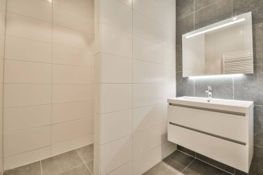 Evdeki modern tuvalette asılı duran banyo musluğu ile duvar arasındaki cam bölme.