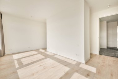 Büyük balkon pencereli, perdeli ve ahşap parke zeminli boş beyaz odanın içi.