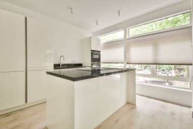 Pencereleri ve ahşap parke zemini olan boş beyaz mutfağın içi.