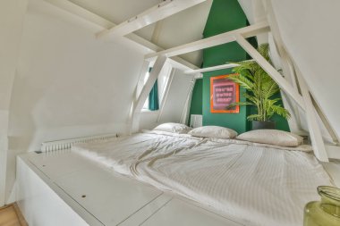 Çağdaş yatak odasının tavan arasında beyaz duvarlar var.