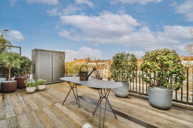 Bright wooden balcony with metal railings, wooden chair and door with glass leads to the kitchen