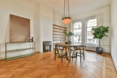 Sandalyeli masa ve rahat kanepe modern dairede şık dekorasyonlarla dolu geniş bir odada.