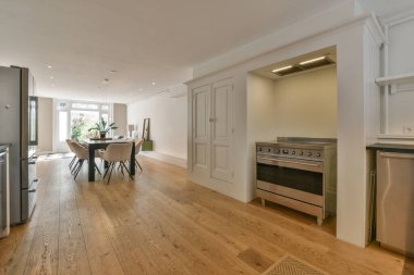 Stüdyo dairesinin modern minimalist tarzı iç tasarımı açık beyaz mutfak ve yemek masası ve sandalyeleri tavan arası lambasıyla aydınlatılmış.