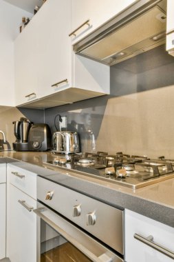 Minimalist tarzı beyaz mobilyalı, lavabolu ve sobalı bir ev mutfağı.