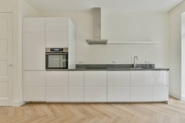 Pencereleri ve ahşap parke zemini olan boş beyaz mutfağın içi.