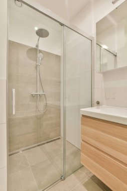 Aynalı lavabo ve temiz küvet modern banyoda cam kapılı ve beyaz fayanslı duvarları olan duş kutusunun yanında.