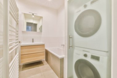 Aynalı lavabo ve temiz küvet modern banyoda cam kapılı ve beyaz fayanslı duvarları olan duş kutusunun yanında.