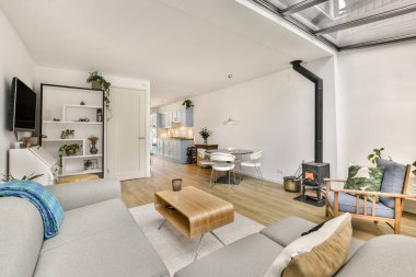 TV 'nin yanındaki koltuklar ve masa, çağdaş apartmandaki geniş odalı yemek alanına karşıdır.