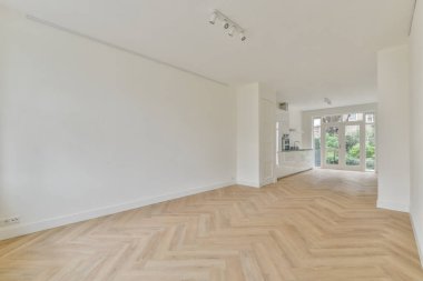 Pencereleri ve ahşap parke zemini olan boş beyaz mutfağın içi.