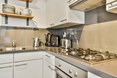 Minimalist tarzı beyaz mobilyalı, lavabolu ve sobalı bir ev mutfağı.