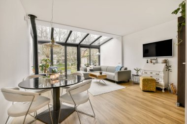 TV 'nin yanındaki koltuklar ve masa, çağdaş apartmandaki geniş odalı yemek alanına karşıdır.