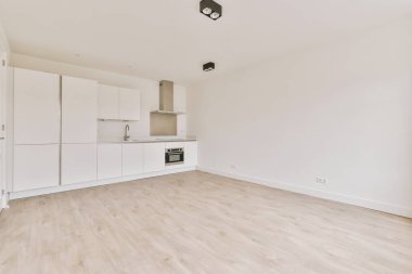 Pencereleri ve ahşap parke zemini olan boş beyaz mutfağın içi.