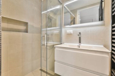 Sinks with mirrors and shower box with glass door in modern bathroom with white tiled walls