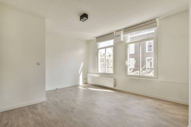 Evdeki boş ışık odasında, beyaz duvardaki plastik pencere ve radyatör.