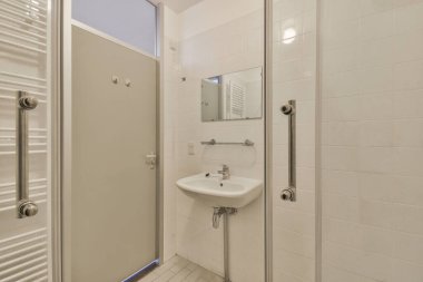 Lavabo ve aynalı dolap kapının yanındaki fayanslı duvara ve modern tuvaletteki kurutma tezgahına bağlı.
