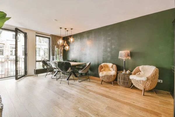 Interior of spacious light dining room and elegant chandelier located near kitchen with modern furniture and appliances