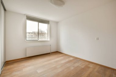 Evdeki boş ışık odasında, beyaz duvardaki plastik pencere ve radyatör.