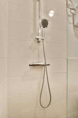 Duş muslukları cam bölmenin yanındaki fayanslı duvara bağlı ve evdeki tuvaletteki süs pervazı.