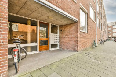 Levhalı, kaldırımlı ve ahşap kapılı bir binanın ön manzarası daireye çıkıyor.