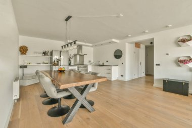 Günümüz minimalist tasarımı. Hafif stüdyo dairesinin ahşap masası ve oturma odası ile beyaz duvarları ve parke zemini arasında yemek masası ve sandalyeleri var.