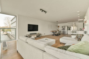 Günümüz minimalist tasarımı. Hafif stüdyo dairesinin ahşap masası ve oturma odası ile beyaz duvarları ve parke zemini arasında yemek masası ve sandalyeleri var.