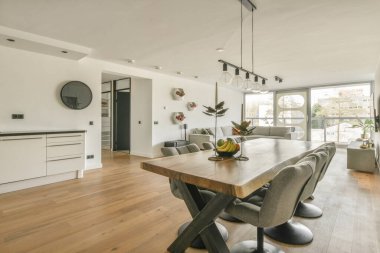 Günümüz minimalist tasarımı. Hafif stüdyo dairesinin ahşap masası ve oturma odası ile beyaz duvarları ve parke zemini arasında yemek masası ve sandalyeleri var.