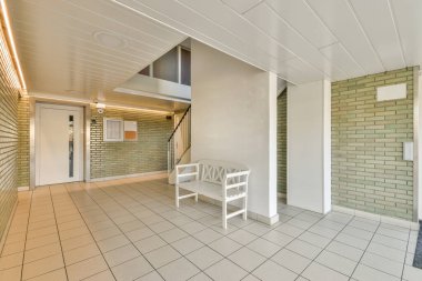 Minimalist iç tasarımı olan modern lüks dairenin ikinci katına çıkan ahşap merdivenli beyaz koridor.