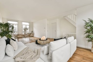 Modern apartmandaki dekorasyonlu ve televizyonlu, rahat koltuğun yanına yerleştirilmiş eski püskü ahşap masa.