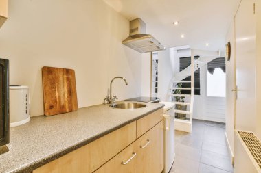 İyi organize edilmiş küçük bir ev mutfağı pencerenin altında lavabo, sobalı hafif mobilyalar ve kentsel apartmanda buzdolabı var.