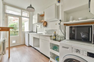 İyi organize edilmiş küçük bir ev mutfağı pencerenin altında lavabo, sobalı hafif mobilyalar ve kentsel apartmanda buzdolabı var.