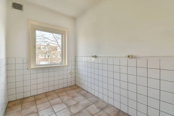 Interior of empty modern apartment with geometric design with entrance door and white and tiled walls and gray tiled floor illuminated with lamp