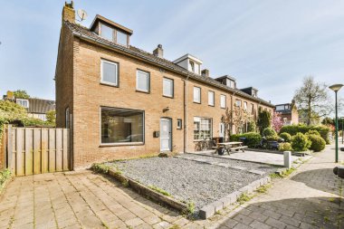 Ağaçlar ve fenerlerle dolu boş bir kaldırım sokağından tuğla evler manzarası