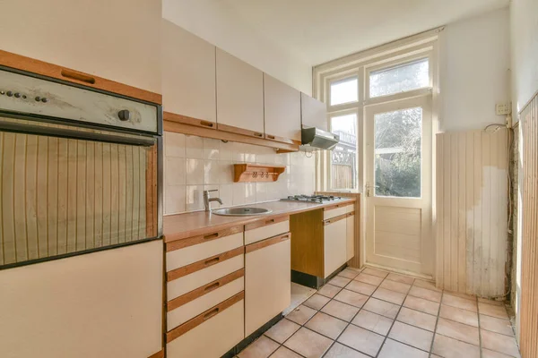 Koridoru ve ahşap parke zemini olan boş, sarımsı bir mutfak.