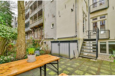 Oturma alanı ve ahşap çitlerin yanındaki küçük bahçesi olan düzgün asfaltlı bir avlu.