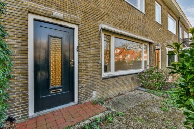 Tabelaları, arabaları, kaldırımları ve ahşap kapıları olan tuğla binanın önü daireye çıkıyor.