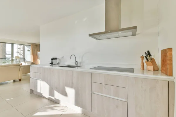 Interior of light kitchen and dining room with balcony doors in contemporary apartment at daytime