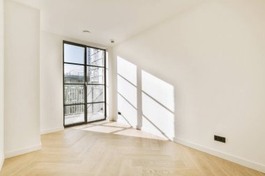 Büyük balkon pencereleri ve ahşap parke zemini olan boş beyaz odanın içi.