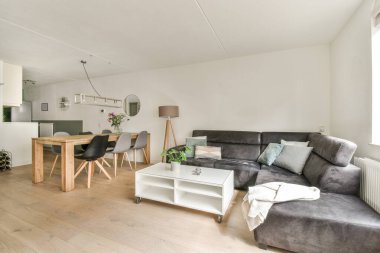 Günümüz minimalist tasarımı. Hafif stüdyo dairesinin ahşap masası ve oturma odası ile beyaz duvarları ve parke zemini arasında yemek masası ve sandalyeleri var.