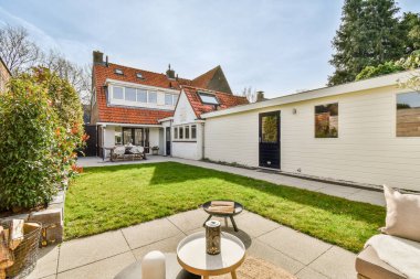 Oturma alanı ve ahşap çitlerin yanındaki küçük bahçesi olan düzgün asfaltlı bir avlu.