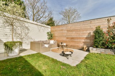Neat paved patio with sitting area and small garden near wooden fence