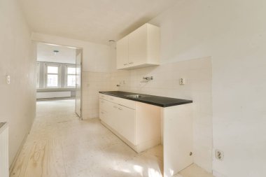 Pencereleri ve ahşap parke zemini olan boş beyaz mutfağın içi.