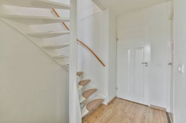 Kapalı beyaz oda kapısı çerçeveli resimlerin yanında ve evdeki merdivenin tepesinde şık bir lamba var.