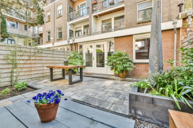 Oturma alanı ve ahşap çitlerin yanındaki küçük bahçesi olan düzgün asfaltlı bir avlu.