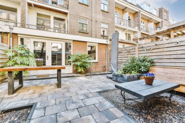 Neat paved patio with sitting area and small garden near wooden fence