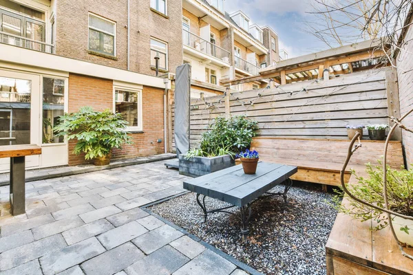 Neat paved patio with sitting area and small garden near wooden fence