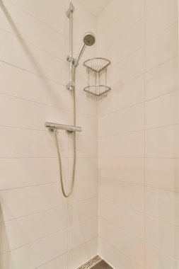 Duş muslukları cam bölmenin yanındaki fayanslı duvara bağlı ve evdeki tuvaletteki süs pervazı.