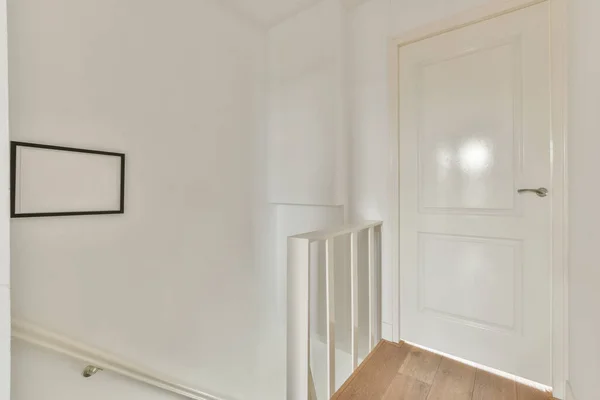 額装された写真の近くにある部屋の白いドアと自宅で階段の上にスタイリッシュなランプ — ストック写真