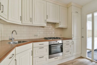 Stüdyo dairesinin modern minimalist tarzı iç tasarımı açık beyaz mutfak ve yemek masası ve sandalyeleri tavan arası lambasıyla aydınlatılmış.